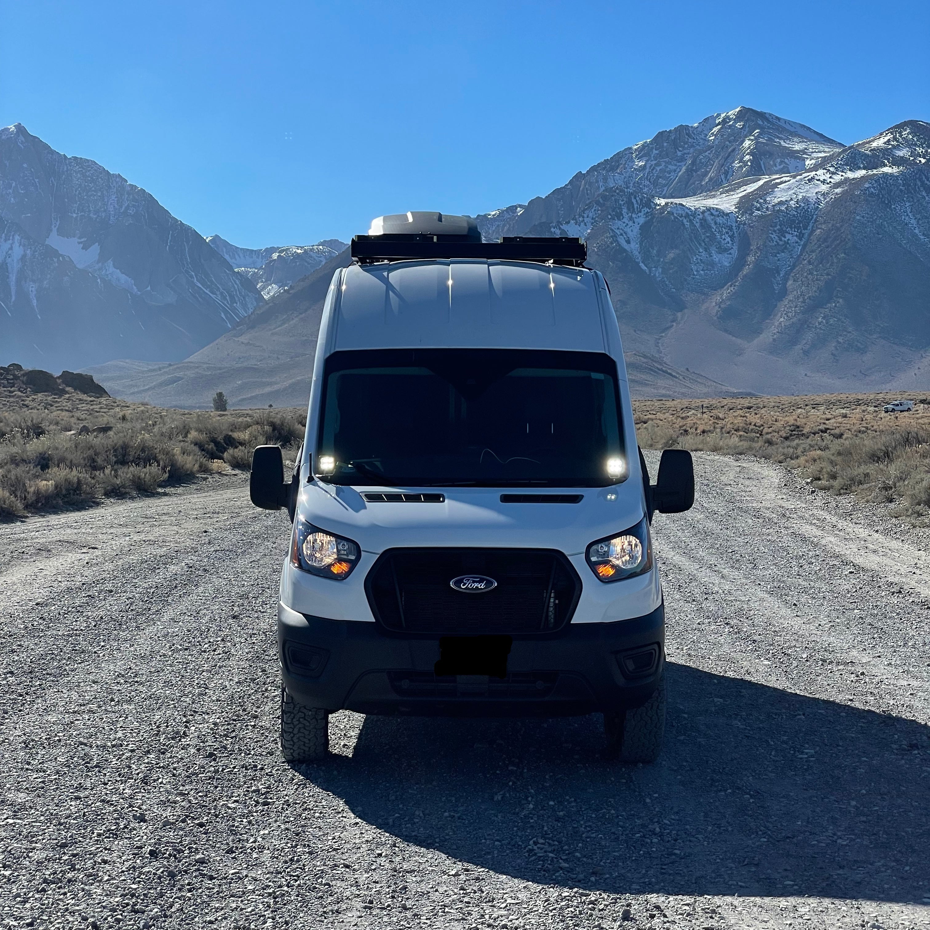 White Transit van on a gravel road with mountains in the background